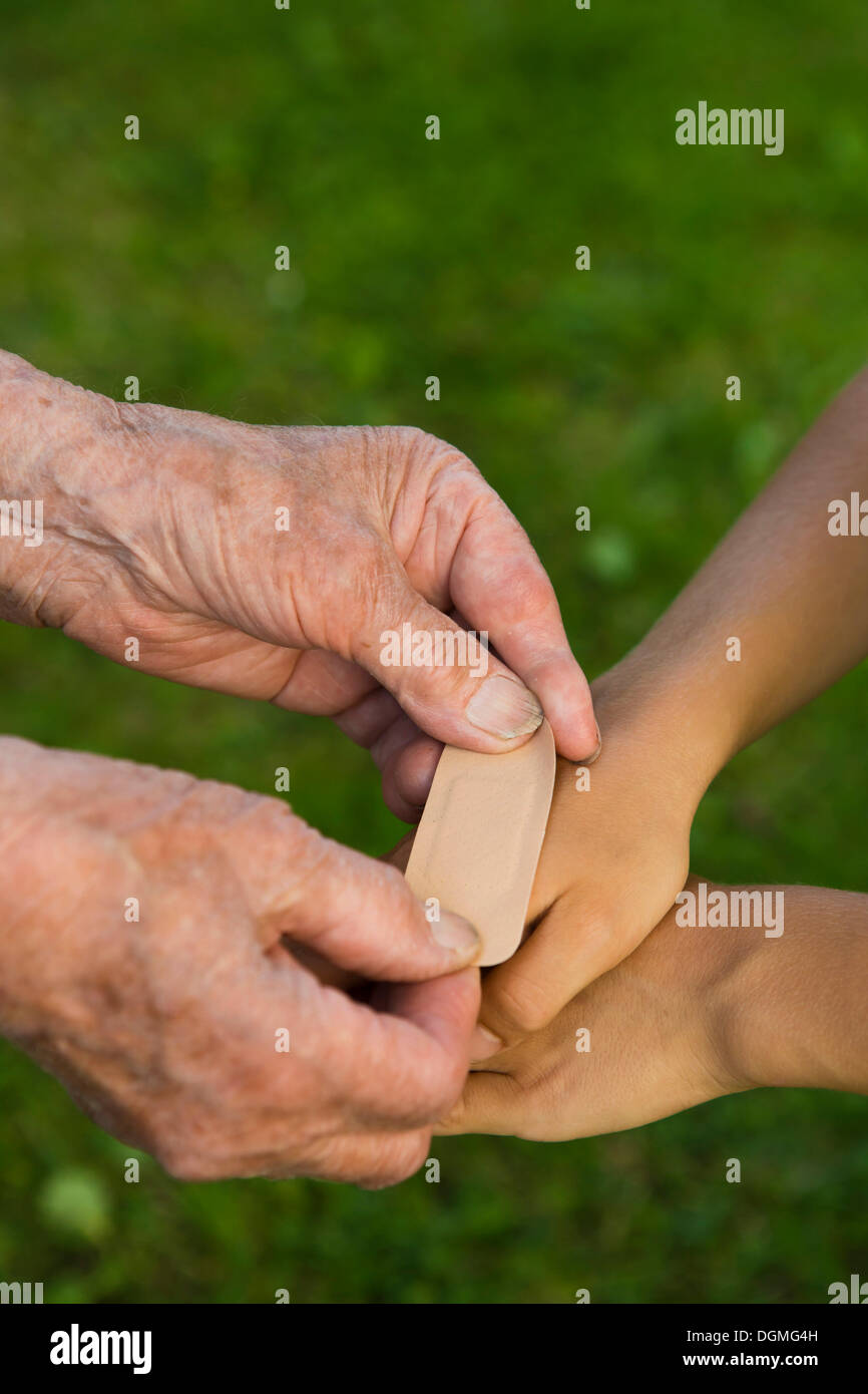 Femme âgée de mettre un pansement sur la main d'un enfant Banque D'Images