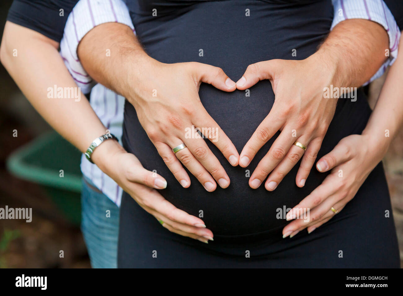 Homme et une femme enceinte formant un cœur avec leurs mains sur son ventre Banque D'Images