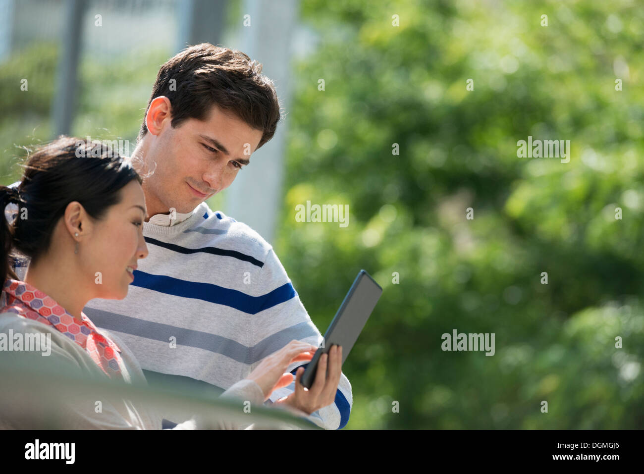 L'été. Les gens d'affaires. Un homme et une femme à l'aide d'une tablette numérique, garder le contact. Banque D'Images