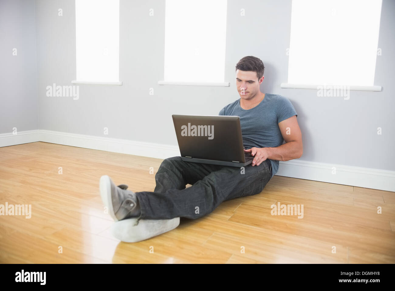 Bel homme pacifique leaning against wall using laptop Banque D'Images