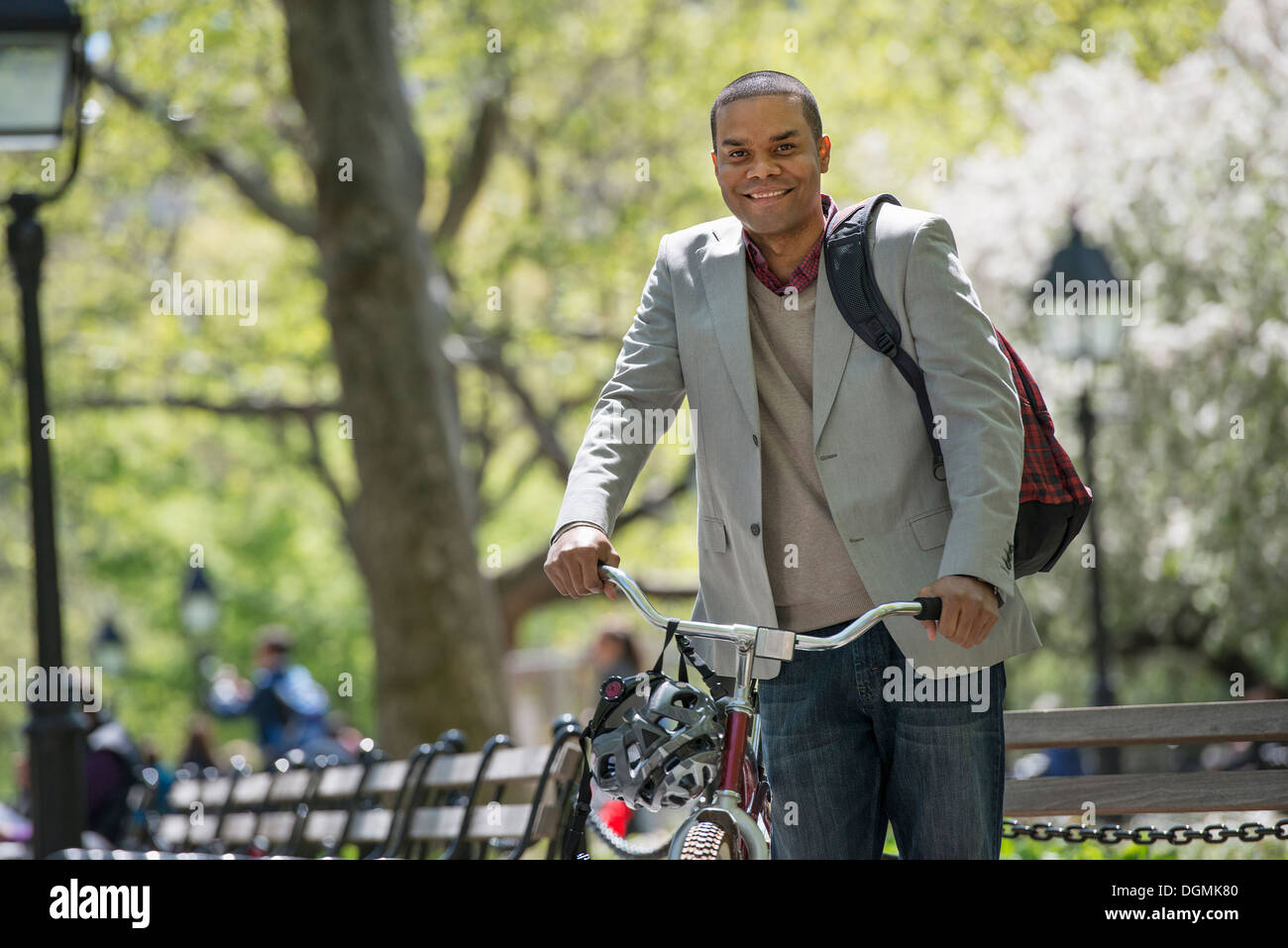 Une famille dans le parc sur une journée ensoleillée. Un homme poussant une bicyclette. Banque D'Images
