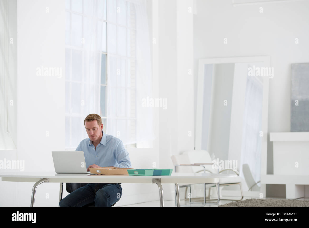 L'entreprise. Un homme assis à un bureau à l'aide d'un ordinateur portable. Banque D'Images