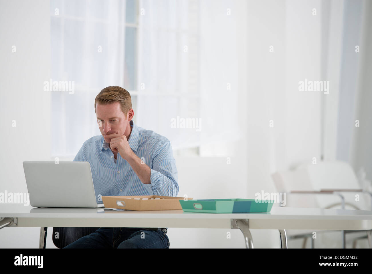 L'entreprise. Un homme assis à un bureau à l'aide d'un ordinateur portable. Banque D'Images
