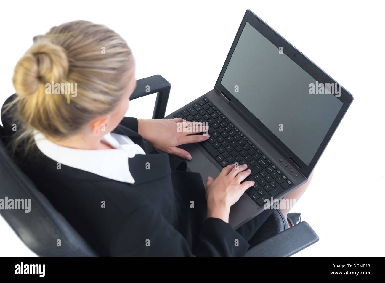 Bien habillé businesswoman sitting concentrée sur sa chaise de bureau à l'aide de son ordinateur portable Banque D'Images