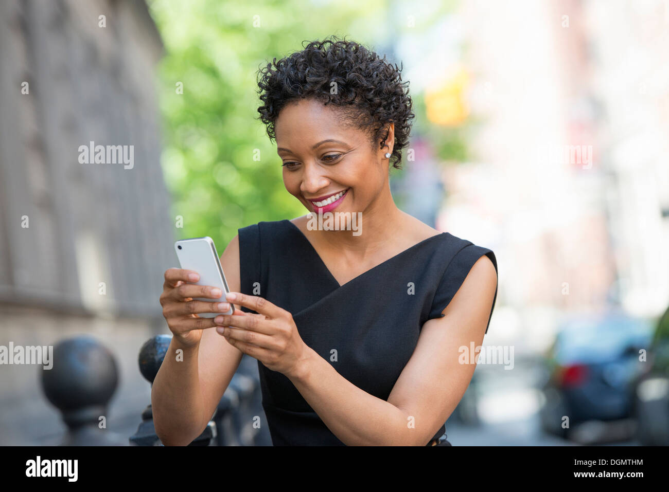 Les personnes en déplacement. Une femme en robe noire sur une rue de la ville, contrôle son téléphone. Banque D'Images