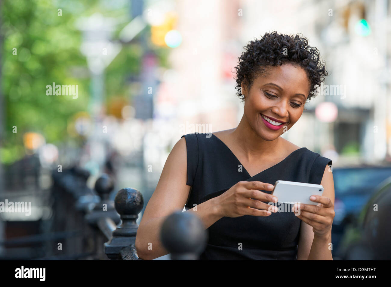 Les personnes en déplacement. Une femme en robe noire sur une rue de la ville, contrôle son téléphone. Banque D'Images