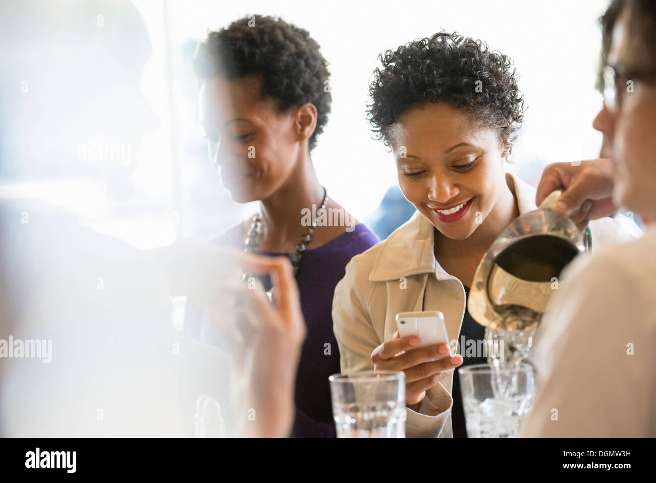 La vie en ville. Un groupe de personnes dans un café, la vérification de leurs téléphones intelligents. Banque D'Images