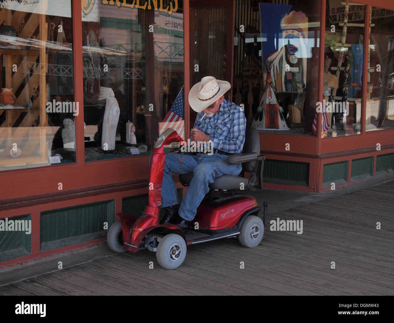 Personnes âgées cowboy dans un fauteuil roulant motorisé allume une cigarette dans le Vieil Ouest Américain historique ville de Tombstone, Arizona, USA Banque D'Images