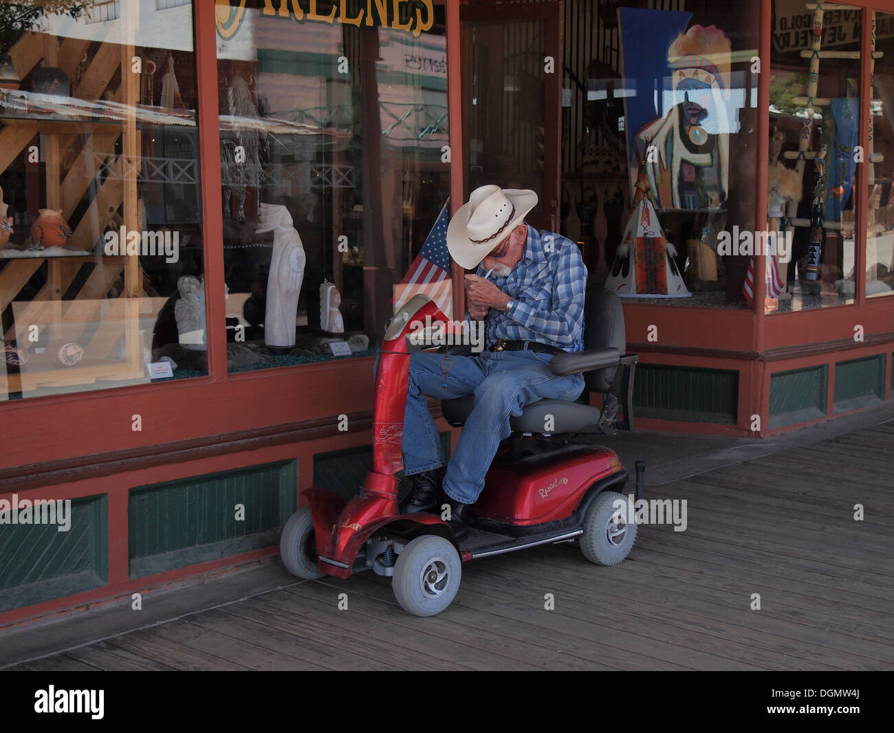 Personnes âgées cowboy dans un fauteuil roulant motorisé allume une cigarette dans le Vieil Ouest Américain historique ville de Tombstone, Arizona, USA Banque D'Images