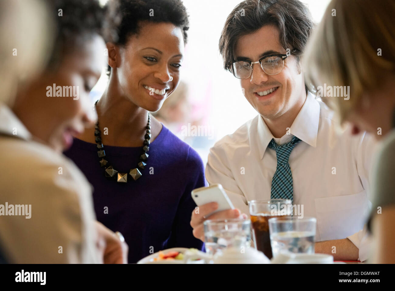 La vie en ville. Un groupe de personnes dans un café, la vérification de leurs téléphones intelligents. Banque D'Images