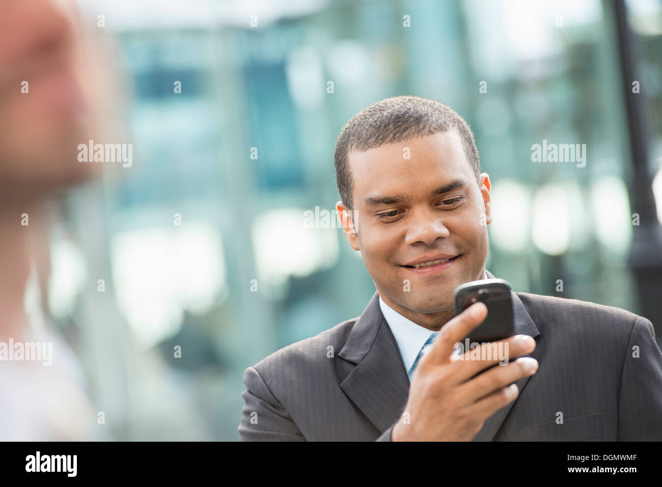 Ville. Un homme dans un costume d'affaires vérifier ses messages sur son téléphone intelligent. Banque D'Images
