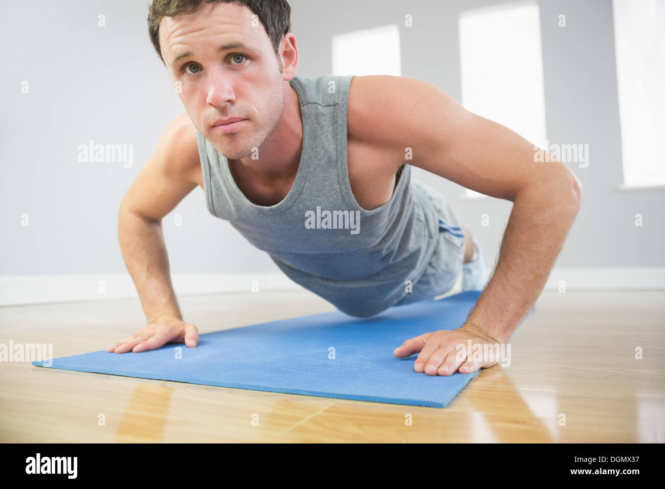 L'homme sportif attrayant faire poussez se lève sur bleu mat looking at camera Banque D'Images