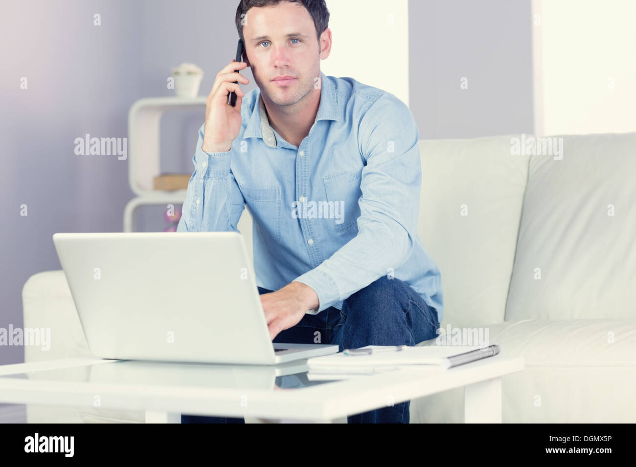 Content casual man using laptop and phoning Banque D'Images