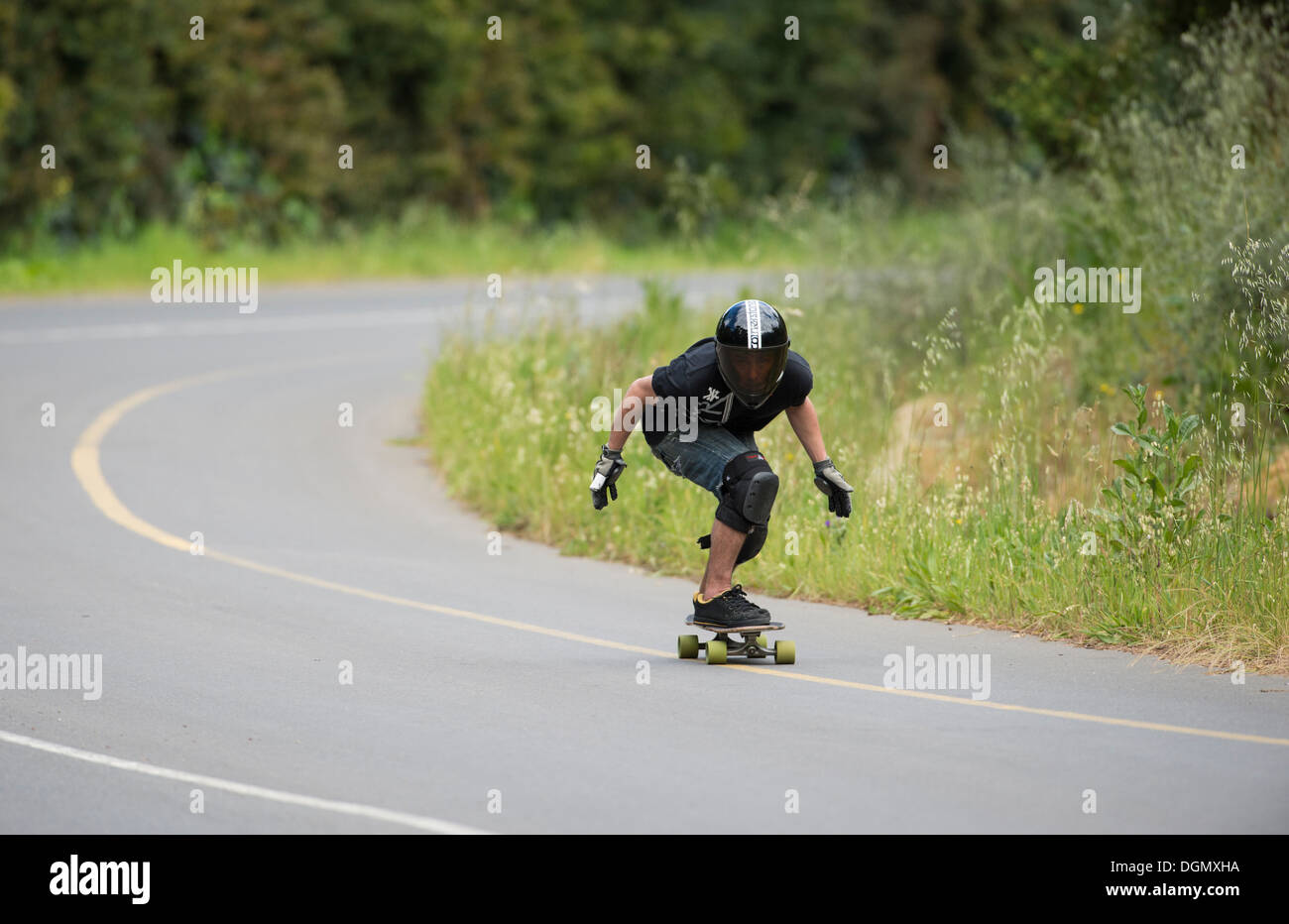 Jeune homme longboard skateboard en formation une courbe en descente sur une route publique Banque D'Images