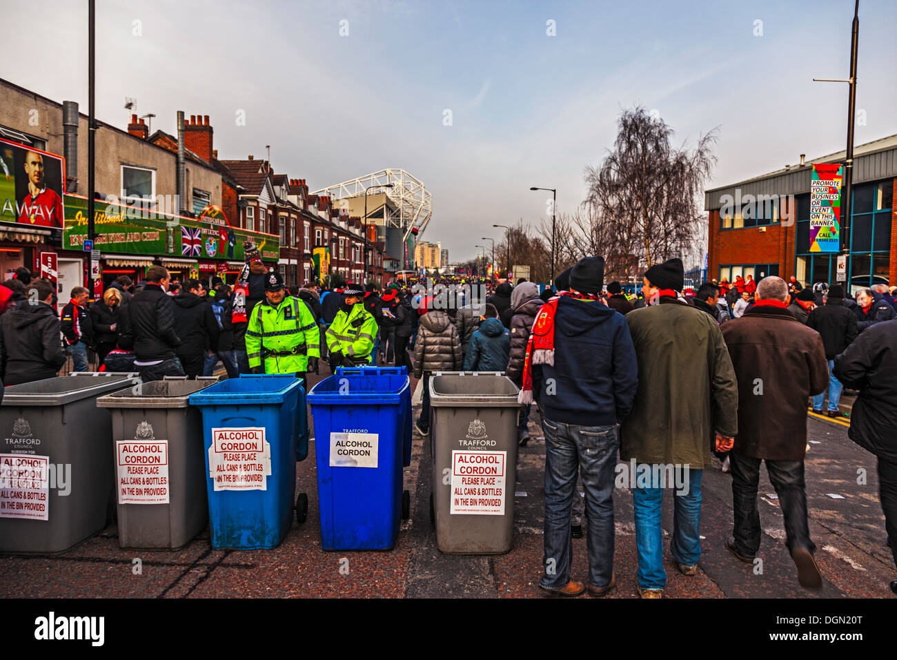 Surveillance d'un cordon de police de l'alcool sur Sir Matt Busby Way à la foule en marche vers le stade de football Old Trafford. Banque D'Images
