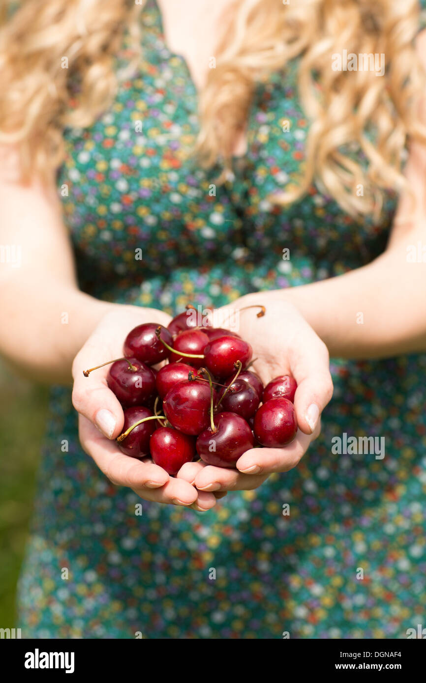 Close up of a blond woman holding quelques cerises Banque D'Images