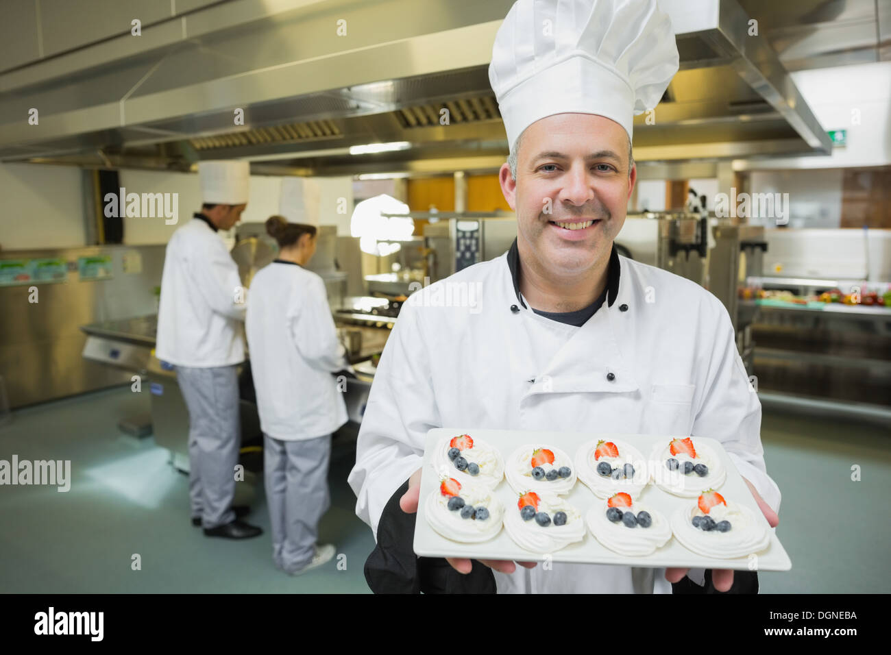 Smiling chef présentant la plaque de meringues fièrement Banque D'Images