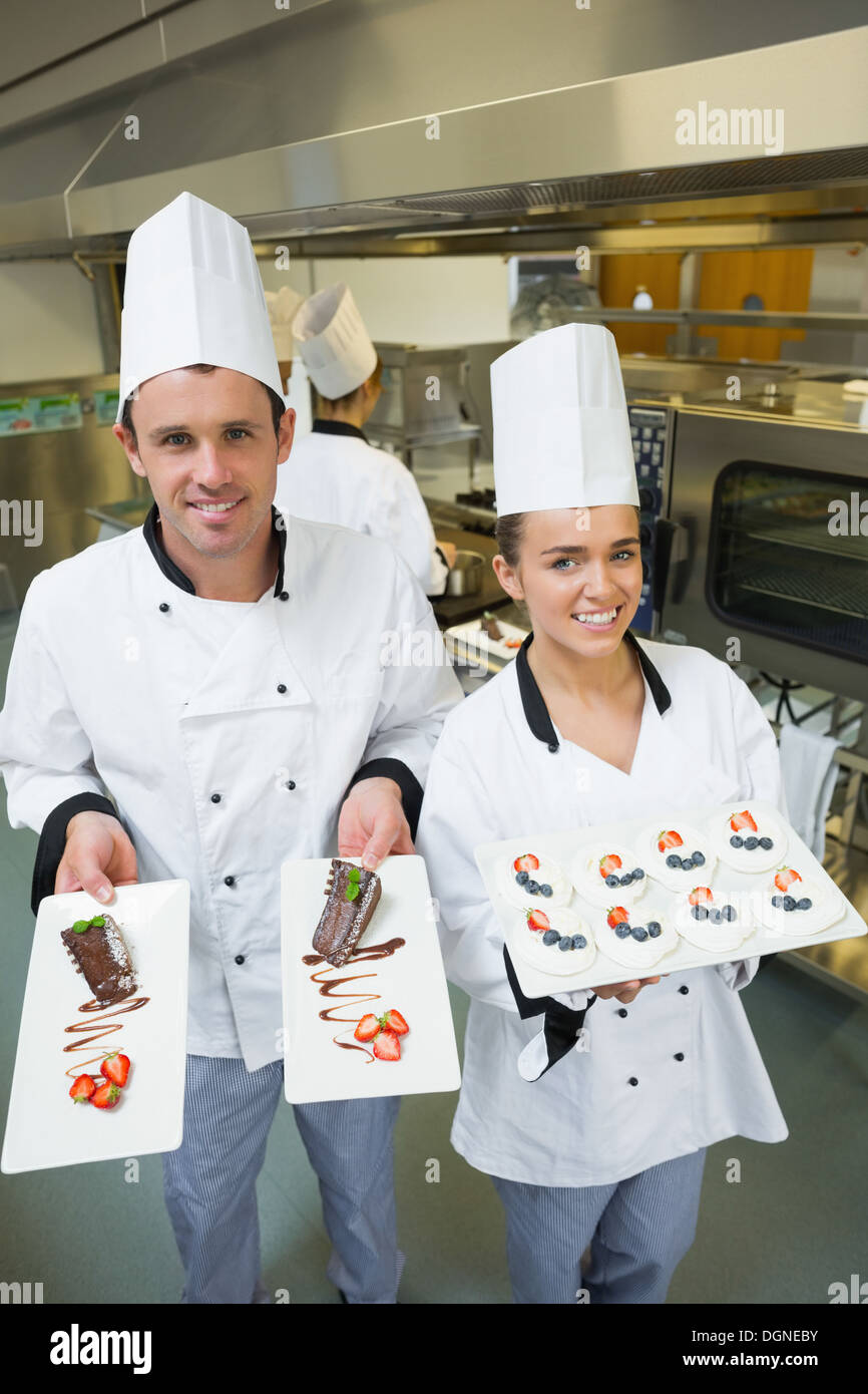 Deux jeunes chefs presenting dessert plates Banque D'Images