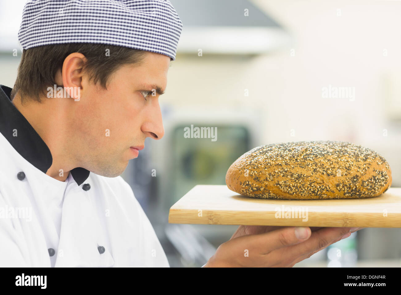 Young baker inspectant une miche de pain semées Banque D'Images