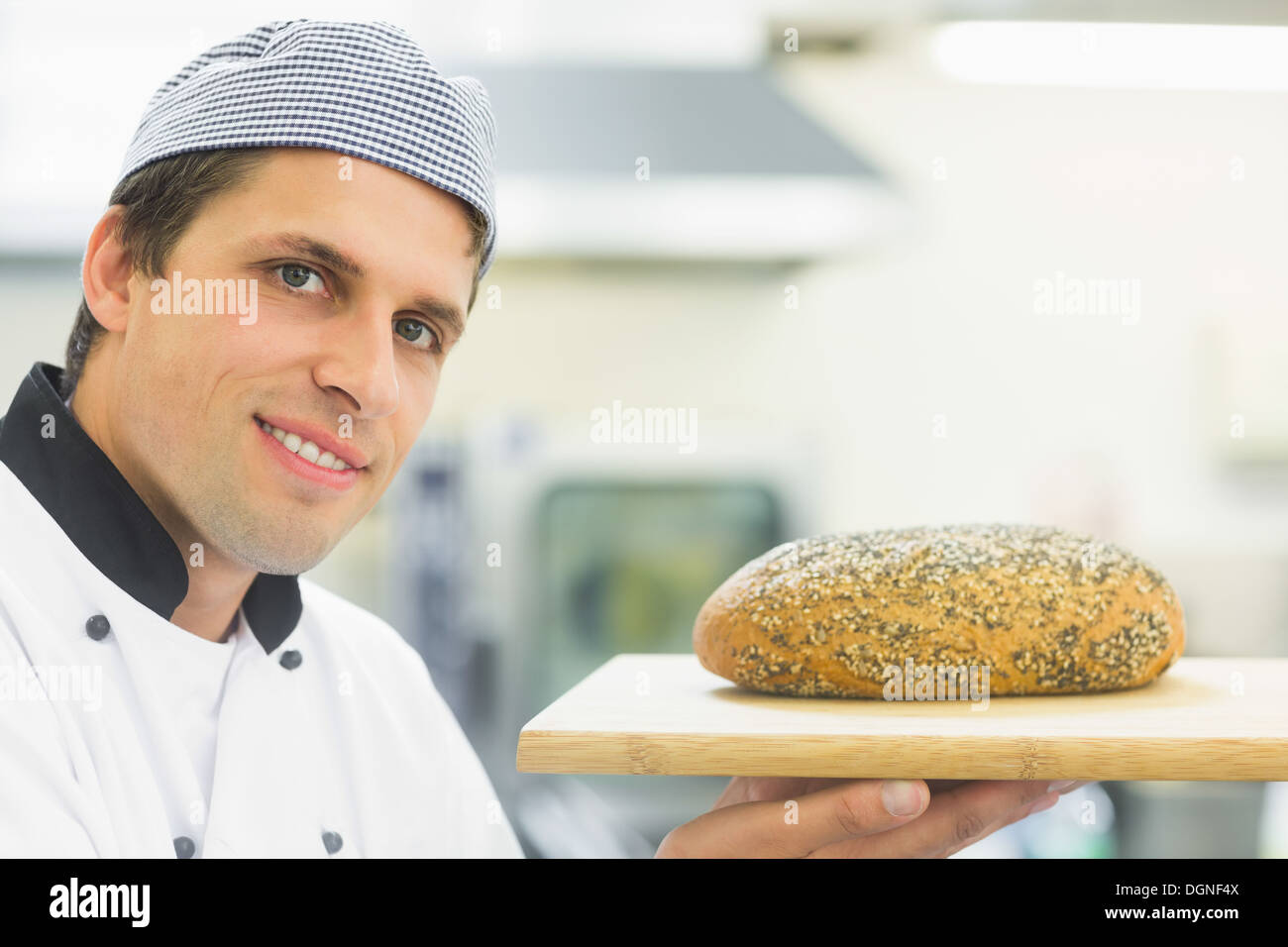 Young baker montrant une miche de pain Banque D'Images
