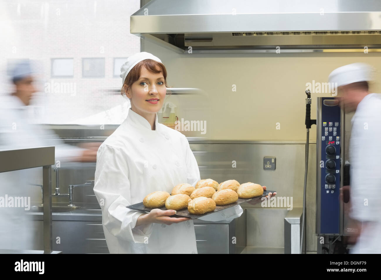 Mignon femelle baker tenant une plaque de cuisson avec rouleaux sur elle Banque D'Images