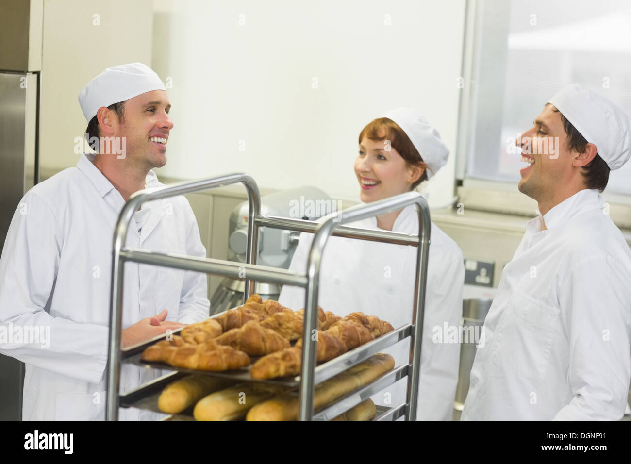 Trois jeunes boulangers chat debout dans une cuisine Banque D'Images