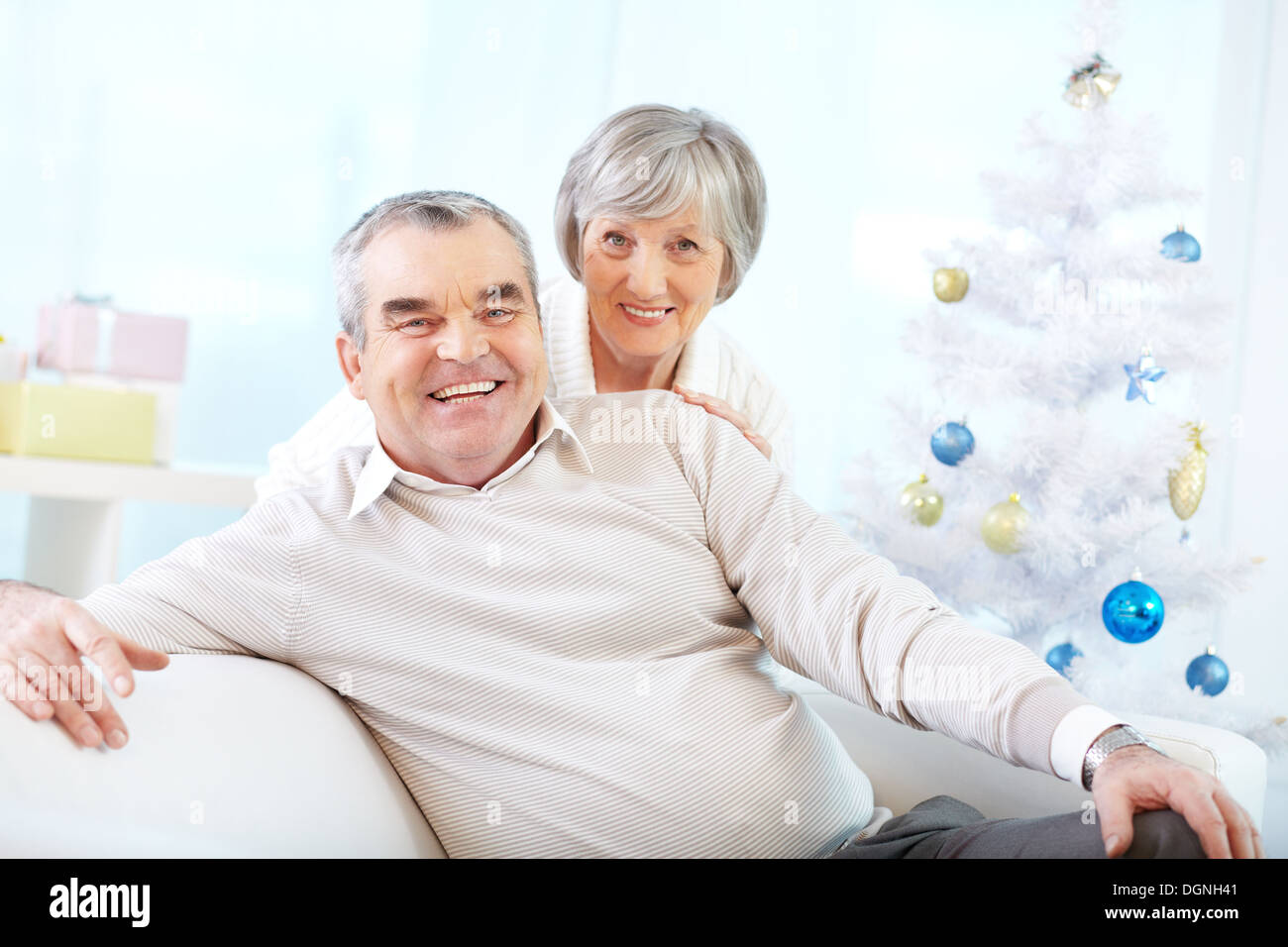 Portrait of a happy senior couple looking at camera sur fond d'arbre de Noël décoré Banque D'Images