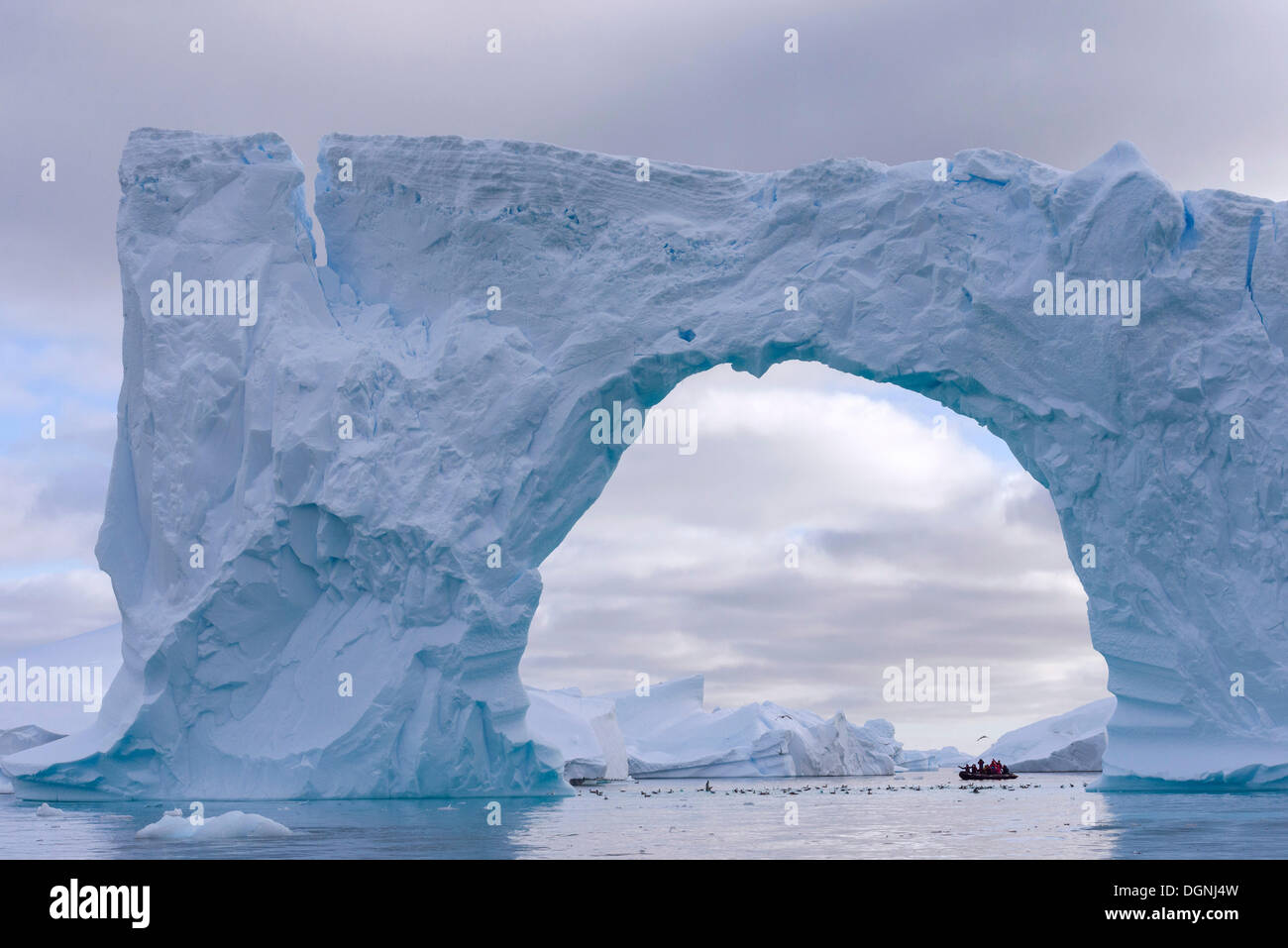 Bateau gonflable Zodiac vu à travers l'arche d'un grand iceberg, Pléneau Bay, péninsule Antarctique, l'Antarctique Banque D'Images