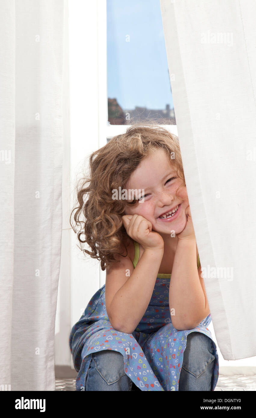 Fille aux cheveux roux, 5 ans, assis et souriant sur l'escalier d'un balcon Banque D'Images