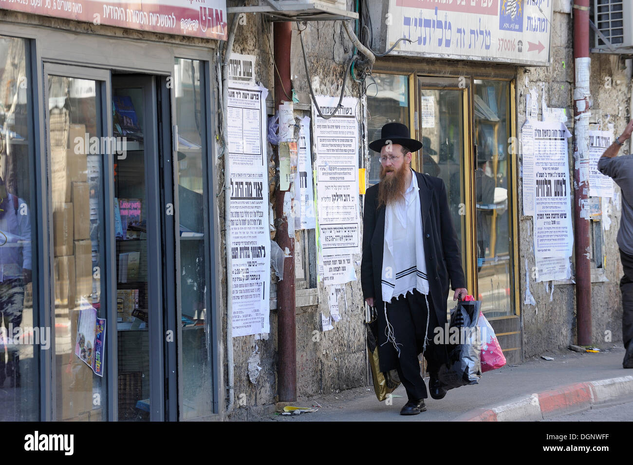 Scène de rue avec un Juif orthodoxe dans l'un me'shéarim district, avec des maisons typiques et journaux muraux, Jérusalem, Israël Banque D'Images