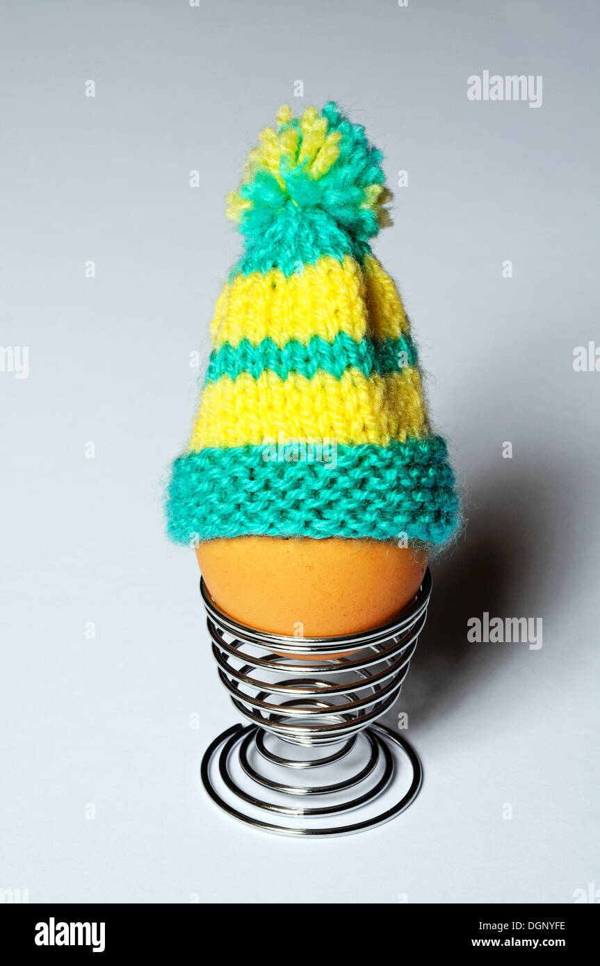 Oeuf dur dans un coquetier en métal surmonté d'un oeuf en tricot confortable. Banque D'Images