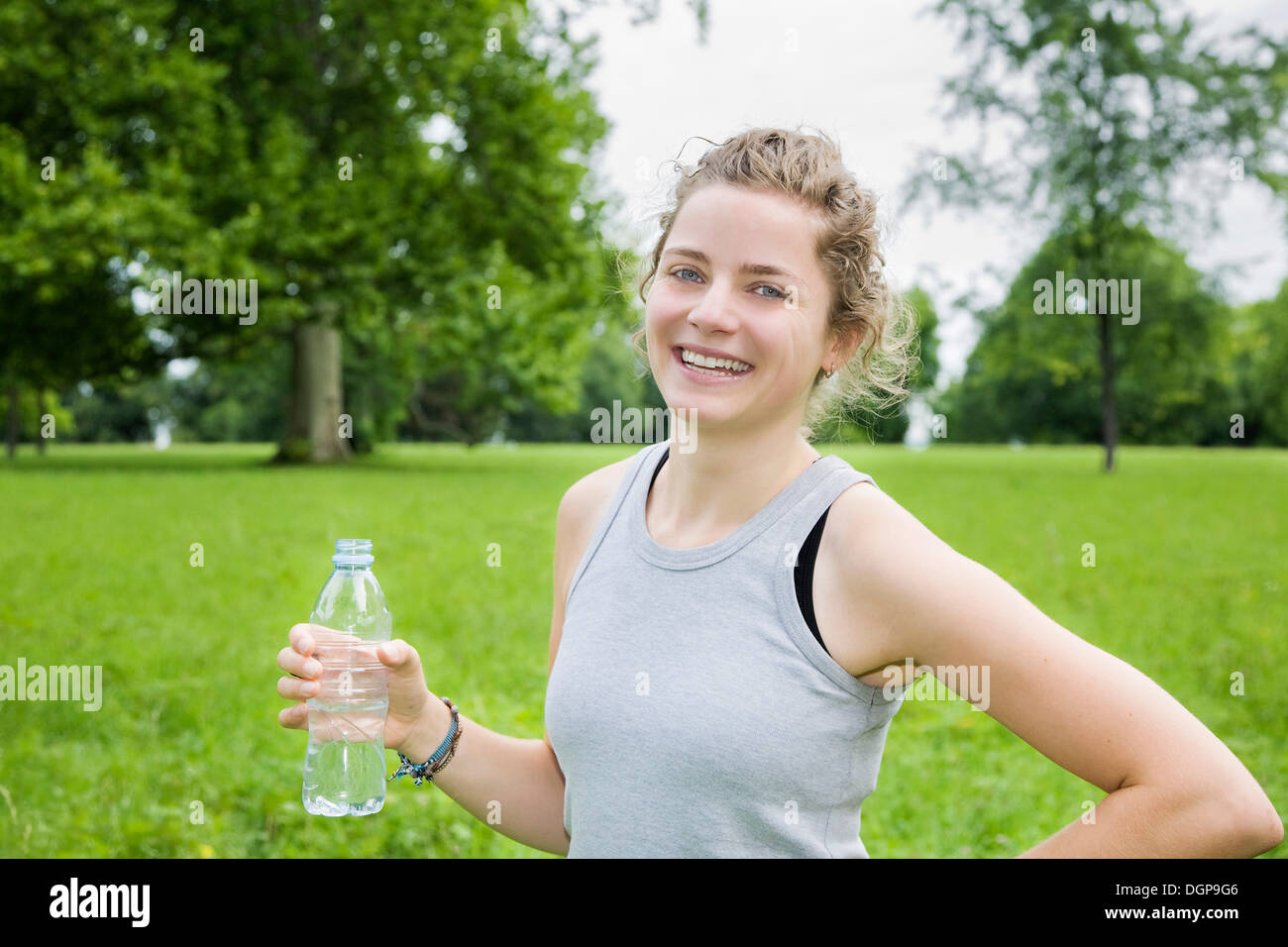 Jeune femme tenant une bouteille d'eau minérale, après l'entraînement Banque D'Images