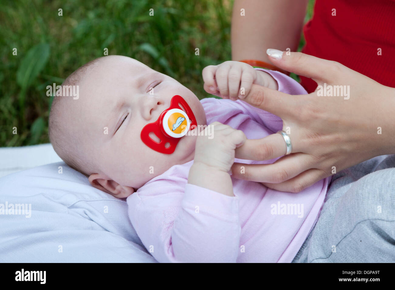 Un bébé de quelques mois, s'accrochant aux doigts de sa mère Banque D'Images