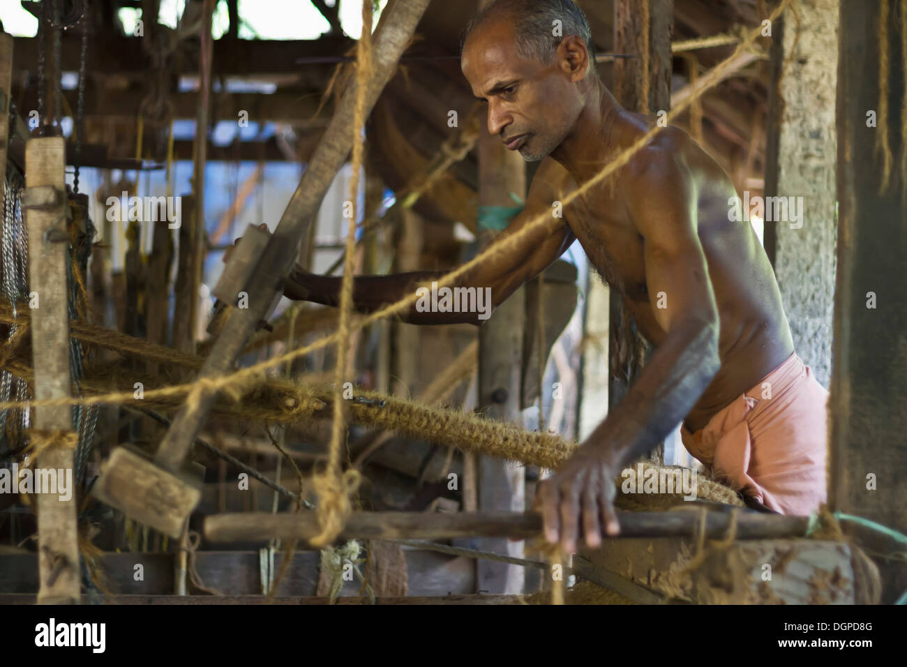 L'Inde, Kerala, Cochin, l'homme travaillant à l'usine de noix de coco paillasson Banque D'Images