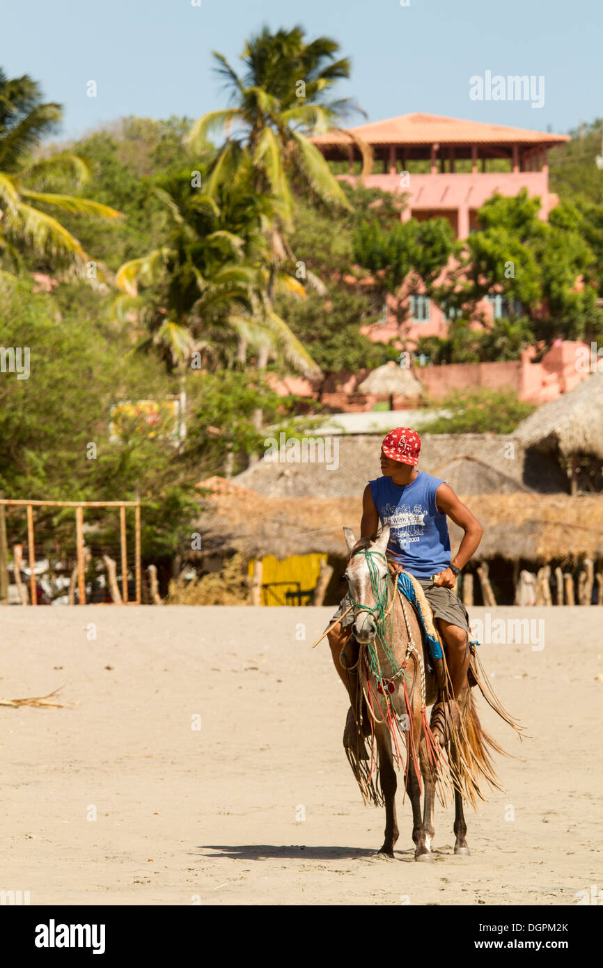 Un homme monté sur un cheval sur la plage Boquita, au Nicaragua. Banque D'Images