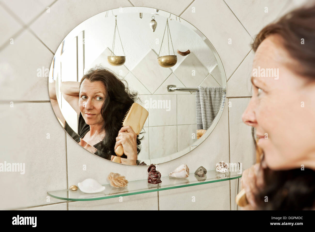 Femme brosser ses cheveux devant un miroir dans la salle de bains Photo Stock Alamy