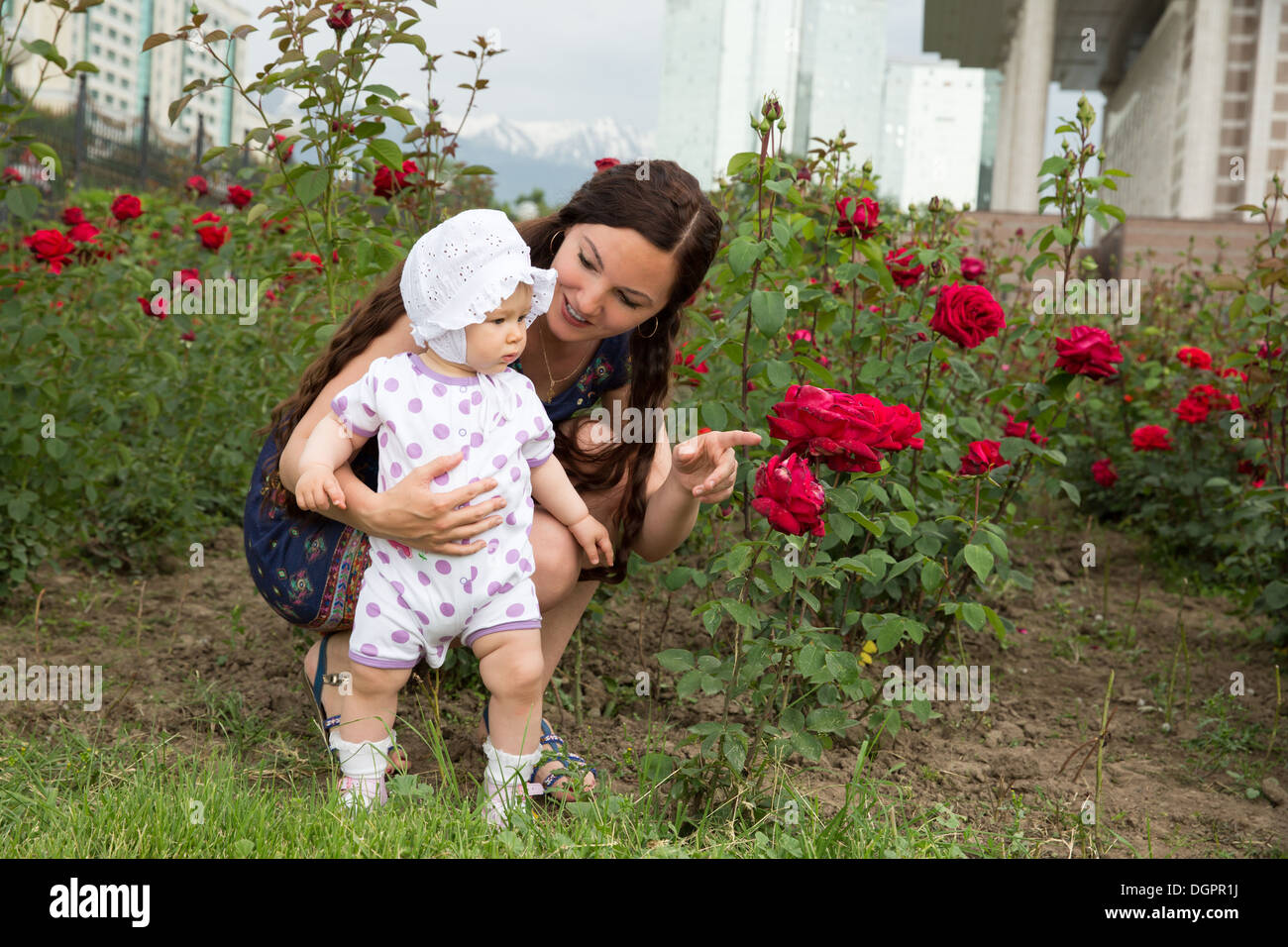 Heureux maman et enfant girl hugging en fleurs. La notion d'enfance et de la famille. Belle Mère et son bébé à l'extérieur Banque D'Images