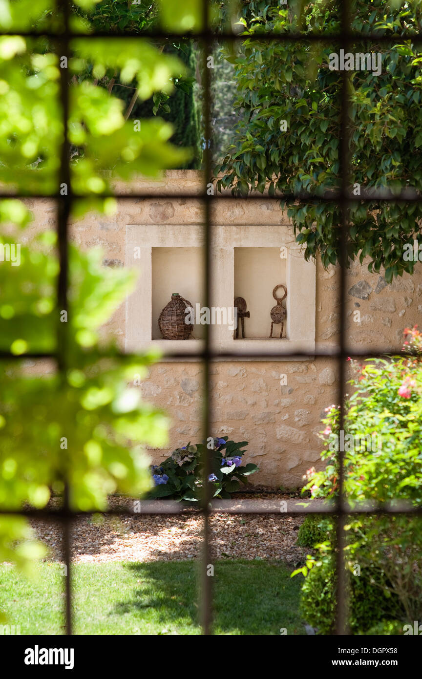 Vue à travers la fenêtre lambris sur cour-jardin avec mur de pierre Banque D'Images