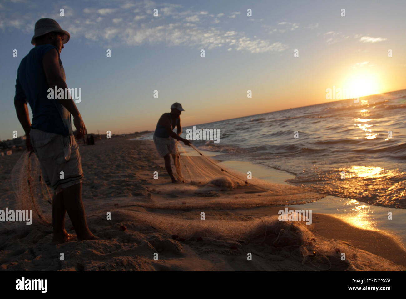 24 octobre 2013 - La ville de Gaza, bande de Gaza, territoire palestinien - Les pêcheurs palestiniens tirer leurs filets de la mer au coucher du soleil sur la plage de la ville de Gaza, le 24 octobre, 2013. Israël restreint la zone de pêche à trois milles marins à la suite de l'enlèvement de Gilad Shalit, soldat israélien en 2007. Les Accords d'Oslo signés en 1993 avec l'Autorité palestinienne stipulent que la zone de pêche de Gaza devrait s'étendre à 20 milles marins. La zone a ensuite été étendu à six milles marins dans le cadre de l'Egyptien cessez-le-feu en novembre 2012, mais Israël par intermittence le réduire à trois milles marins Banque D'Images