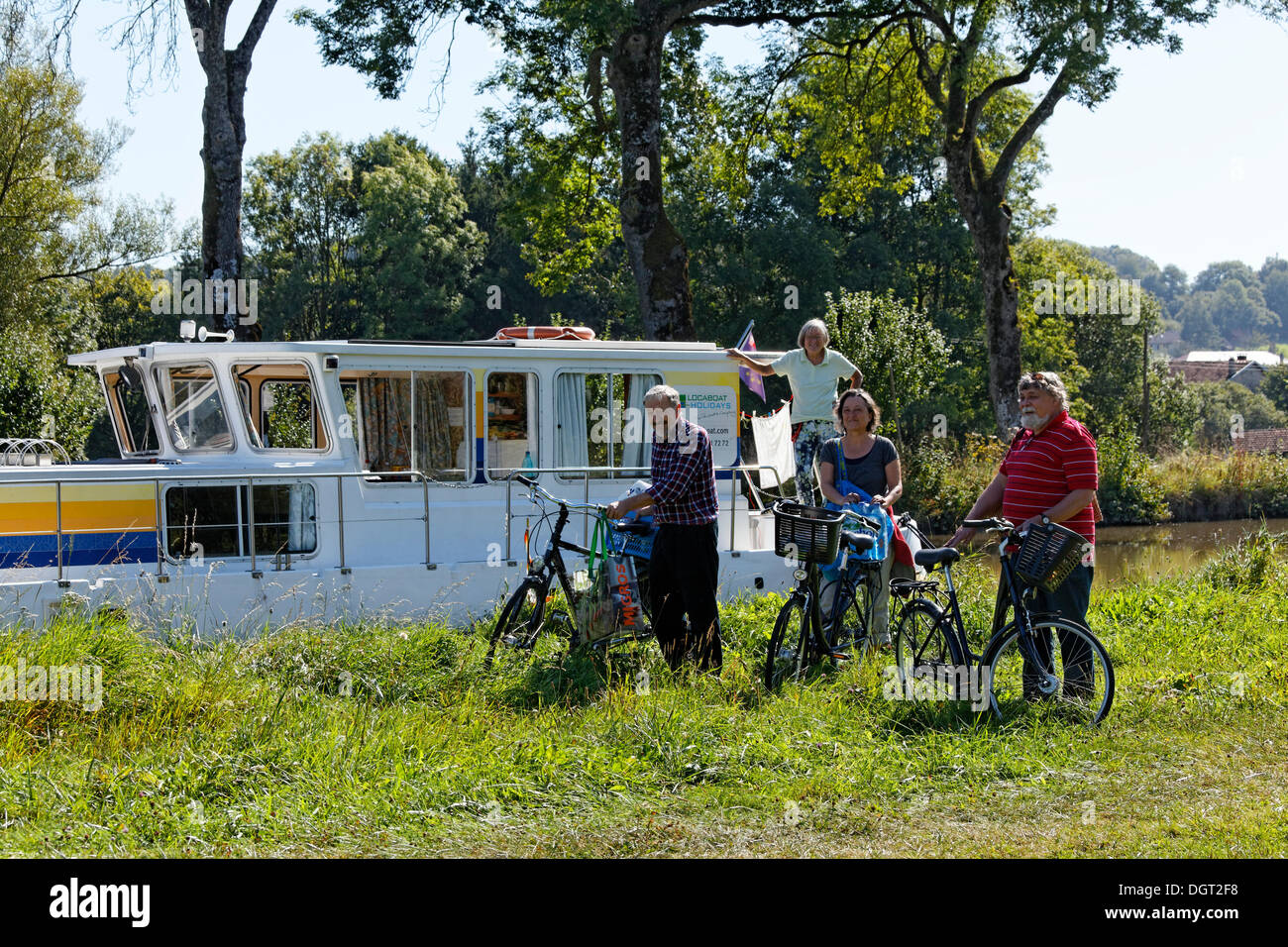 Les vacanciers en face d'une maison bateau sur le canal des Vosges, anciennement Canal de l'Est, après faire du shopping à vélo Banque D'Images