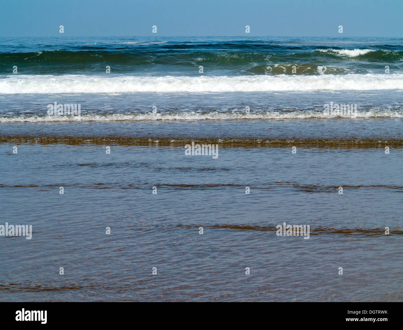 Détails sur une plage de petites vagues se brisant sur une plage de sable de créer des bandes horizontales de couleur et texture Sidi Ifni Maroc Banque D'Images
