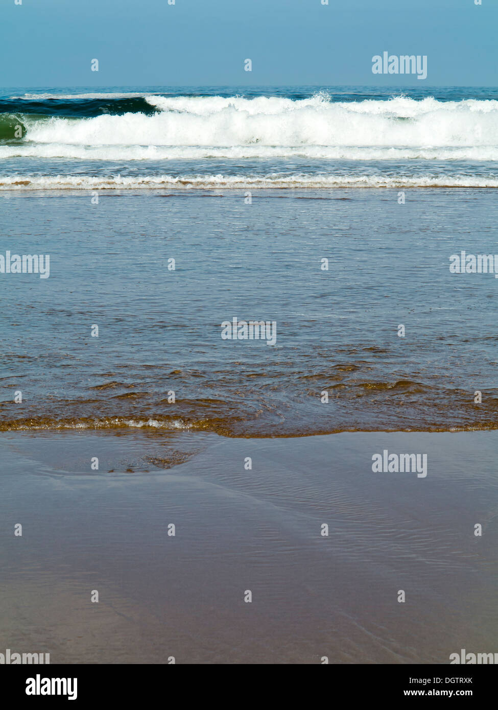 Détails sur une plage de petites vagues se brisant sur une plage de sable de créer des bandes horizontales de couleur et texture Sidi Ifni Maroc Banque D'Images