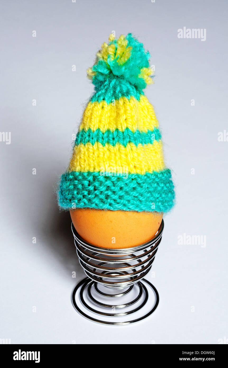 Oeuf dur dans un coquetier en métal surmonté d'un oeuf en tricot confortable. Banque D'Images