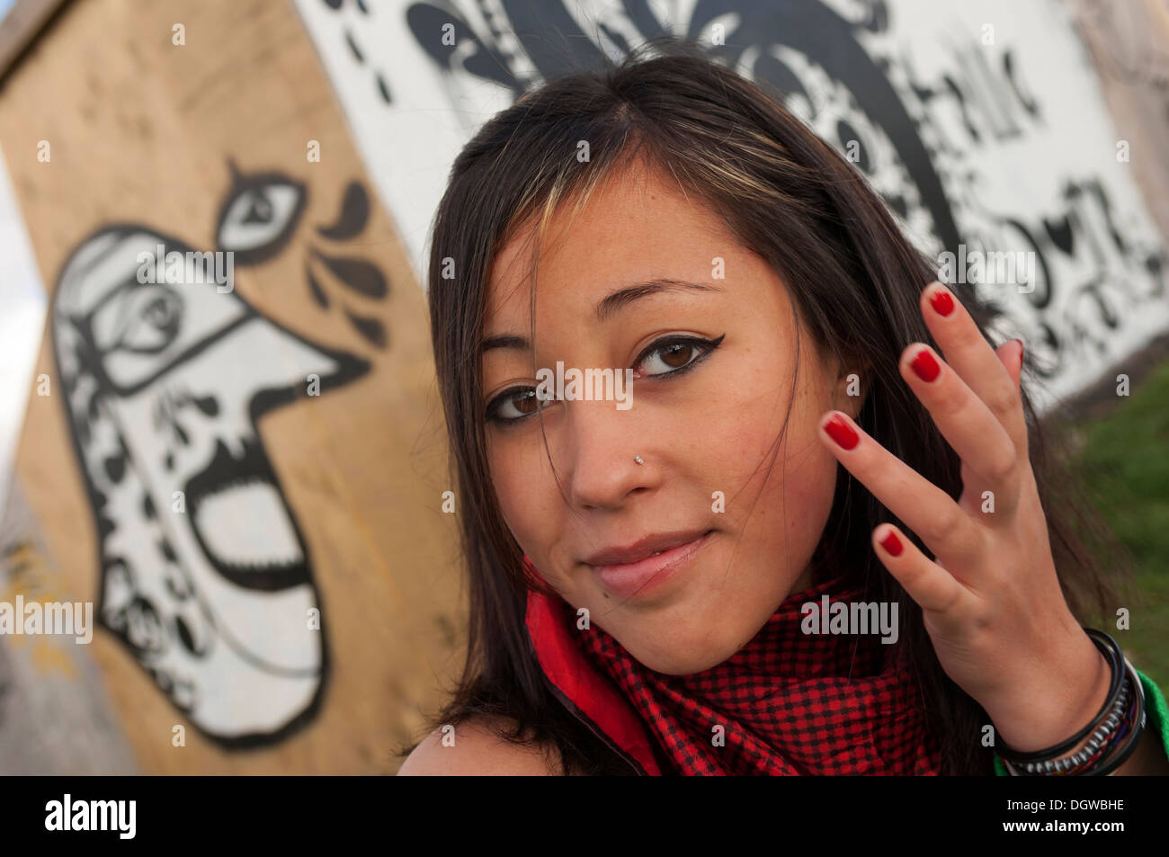 Une adolescente se tenait à côté de certains graffiti urbain looking at camera Banque D'Images