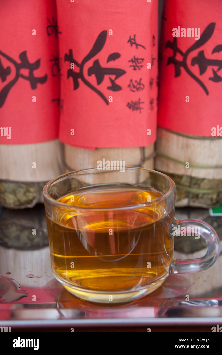 Thé vert, tasses à thé, feuilles de thé comprimé enveloppé dans une bande rouge avec l'écriture chinoise, Pu'er, Jiangcheng City, province du Yunnan Banque D'Images