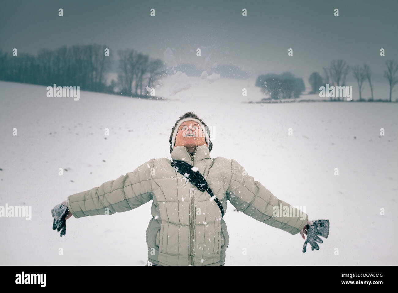 Femme d'âge moyen extatique profiter de la neige en hiver. Banque D'Images