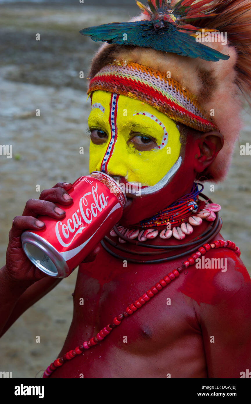 Colorées et peint boy drinking from un Coke peut pendant la traditionnelle chanter chanter dans les highlands, Enga Banque D'Images