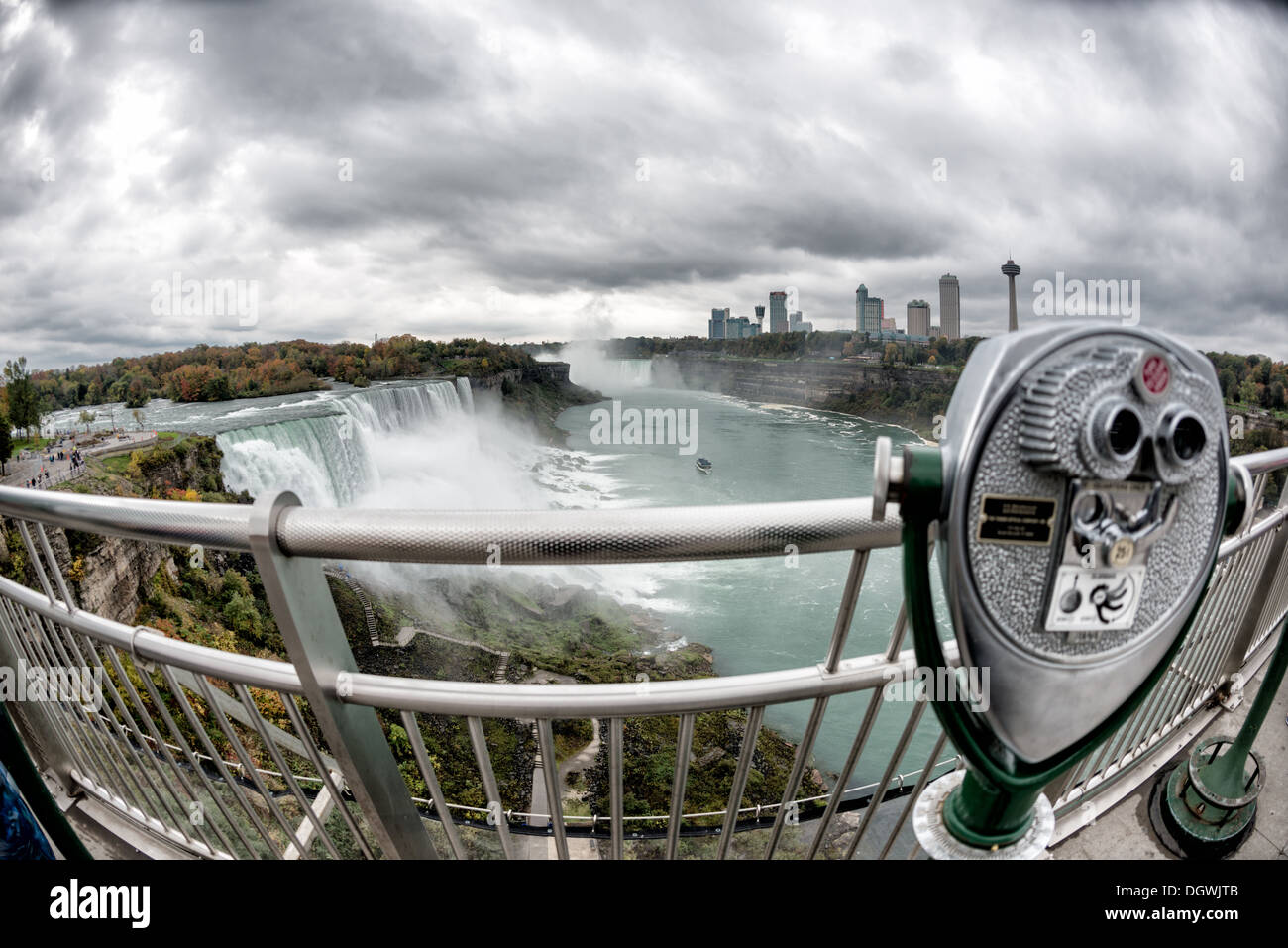 Plateforme d'observation du télescope de Niagara Falls en automne | NIAGARA FALLS, New York, États-Unis — Un télescope payant sur une plateforme d'observation encadre une vue en fisheye des chutes américaines et des chutes du Cheval de Prêles, avec la ligne d'horizon de l'Ontario et la tour Skylon au-delà en automne. La gorge de la rivière Niagara en contrebas a été creusée à des profondeurs d'environ 180 pieds (55 m) par les eaux de fonte glaciaires à la fin de la dernière période glaciaire. Banque D'Images