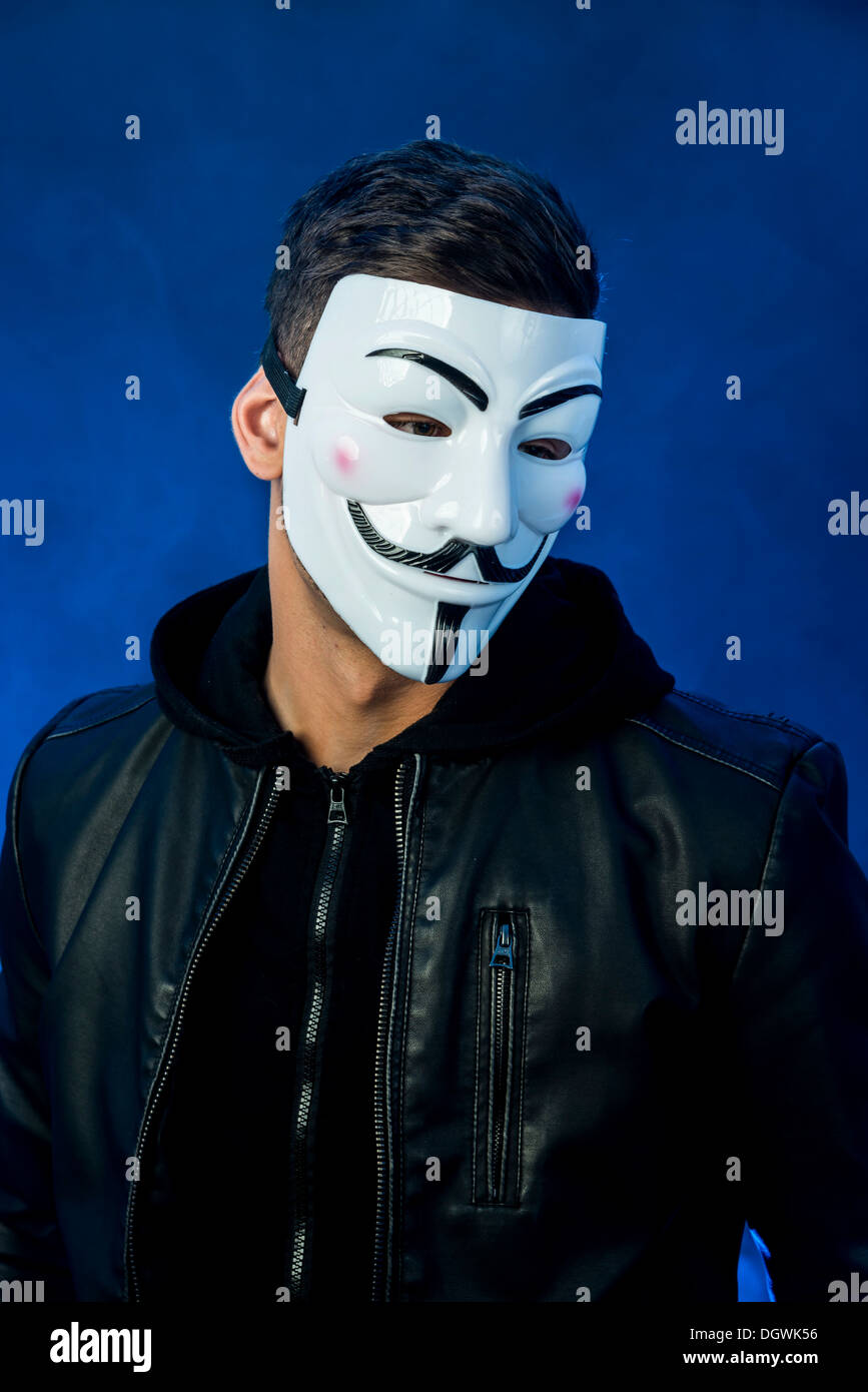 Jeune homme portant un masque anonyme et une veste en cuir noir Banque D'Images