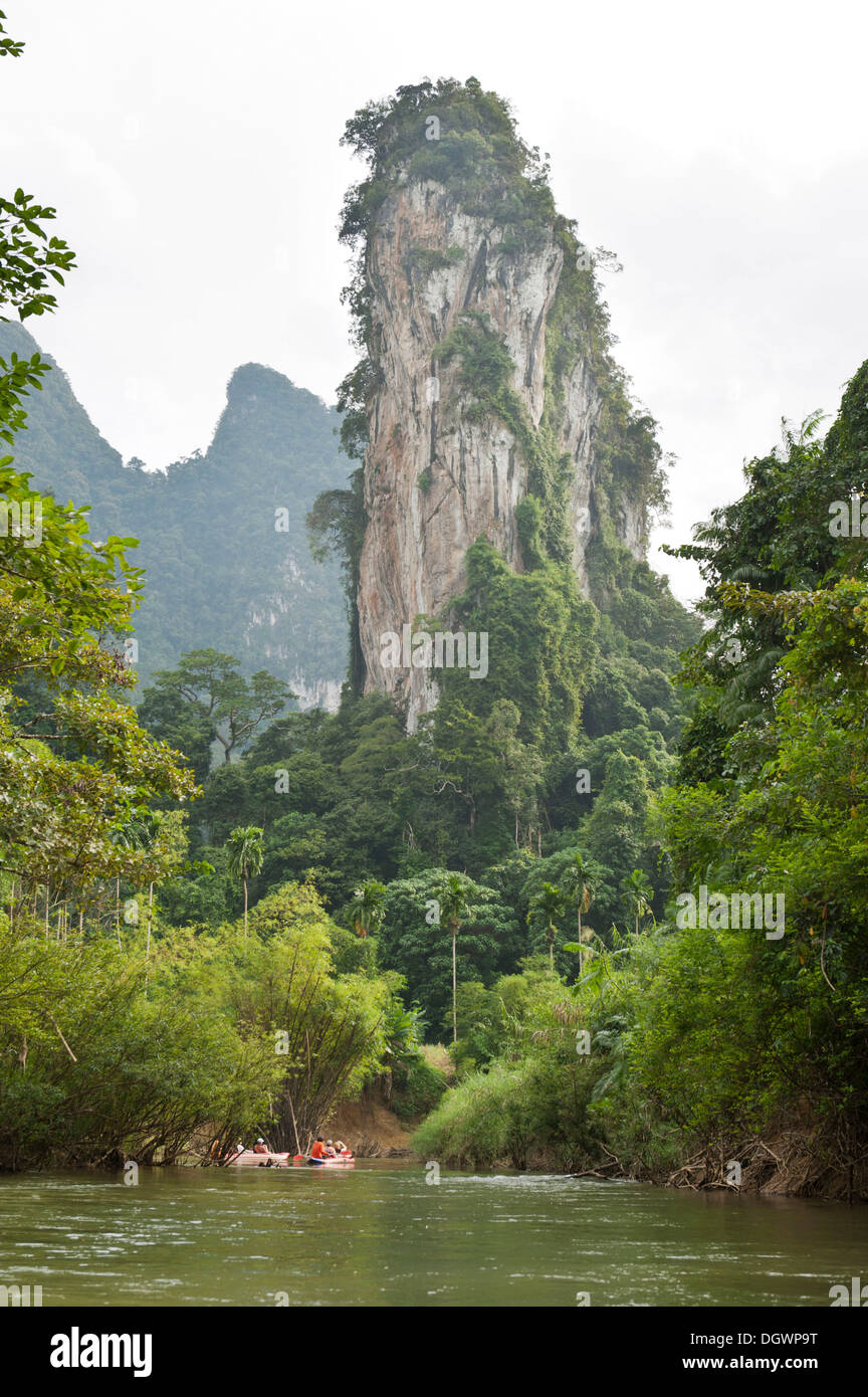 Les kayakistes de l'aviron sur une rivière à travers la jungle, avec un paysage karstique pinnacle rock s'élevant au-dessus de eux Banque D'Images